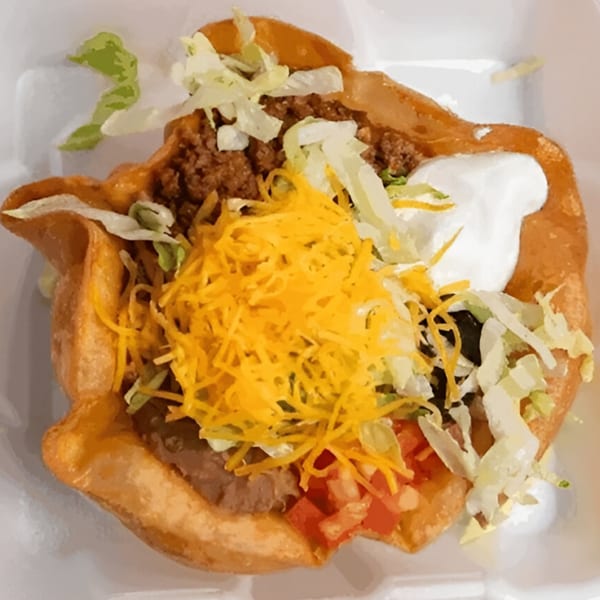 A Pepe's Mexican Café taco salad in a crispy shell with meat, cheese, lettuce, and sour cream.