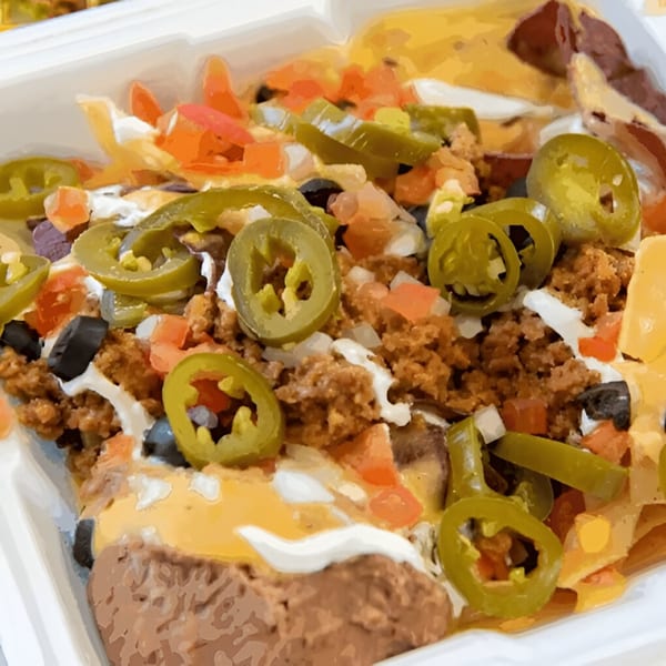 Close-up of Pepe's Mexican Café nachos with ground beef, jalapeños, tomatoes, and sour cream.